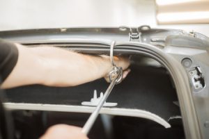 man works on dent on car with paintless dent repair technique